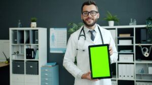 Medico sorridente con tablet in mano in studio, contesto agenda appuntamenti online