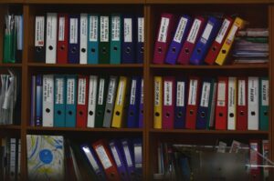 Archivio di faldoni cartacei colorati su scaffali in uno studio medico, simbolo della gestione pazienti prima della digitalizzazione